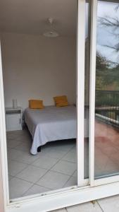 Una cama con almohadas amarillas en una habitación con ventana. en L'appartement de Clothilde, en Villefranche-de-Rouergue