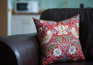 a red pillow sitting on a brown couch at Grade II listed 3 bed townhouse in Exeter, Devon in Exeter