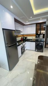 a kitchen with white cabinets and a stainless steel refrigerator at Doki sky suite in Cairo