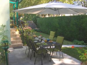 a table and chairs under an umbrella in a garden at Chambre d'hôtes Au Canal in Illkirch-Graffenstaden