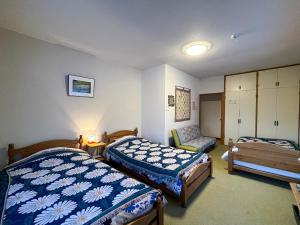 een slaapkamer met twee bedden en een stoel erin bij Natsumi no Sato in Biei