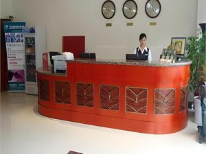 a man standing behind a red counter in a store at GreenTree Inn Jinan Bus Terminal in Jinan