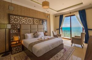 een slaapkamer met een groot bed en een groot raam bij Golden Tulip Zanzibar Resort in Zanzibar City