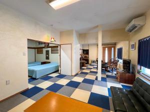 een woonkamer met een blauw bed en een geblokte vloer bij Natsumi no Sato in Biei