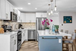 a kitchen with white cabinets and a blue island at Hip Oceanfront Resort Vistas in Kihei +44 photos