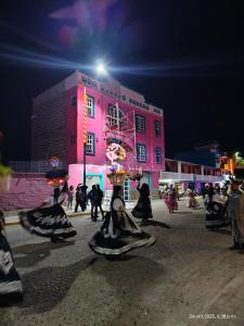 La casa se los abuelos في San Pablo Villa de Mitla: مجموعة من الأشخاص يرتدون أزياءً أمام مبنى وردي اللون