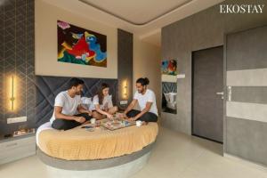 a group of four people sitting on a bed at EKOSTAY - Terra Cotta Villa in Panchgani