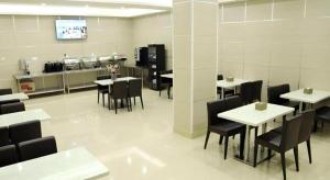 GreenTree Inn Jiangsu Changzhou Henglin Town Shuntong Road Express Hotel في تشانغتشو: غرفة طعام مع طاولات بيضاء وكراسي سوداء