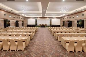 Una gran sala con filas de sillas y mesas blancas. en Hotel Pangeran, en Pekanbaru 241 fotos más