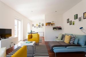 uma sala de estar com um sofá azul e uma cadeira amarela em ALTIDO Joyful 2BR Apt with terrace nearby São Bento Palace em Lisboa
