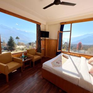 a bedroom with a bed and a large window at Hotel Suraj Inn ,near Hadimba Devi Temple ! Rooftop Restaurant ! Personal Parking in Manāli