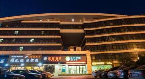 City Comfort Inn Wuhan High Speed Railway Station في ووهان: مبنى كبير مع سيارات متوقفة أمامه
