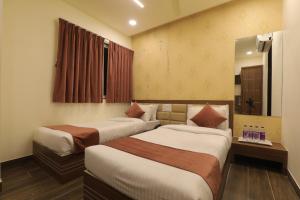 una camera d'albergo con due letti e uno specchio di Hotel Shiv Shakti a Rajkot Altre 9 foto