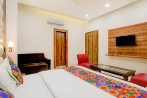 a hotel room with a bed and a desk and a television at FabHotel The Elegant - 150 Meters From Delhi Public School Meerut in Anūpnagar