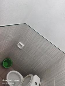 a bathroom with a toilet and a green trash can at Reefside Retreat by B'lu Bamboo in Moalboal