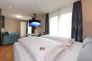 a hotel room with a white bed and a television at Design & Lifestyle Hotel Estilo in Aalen