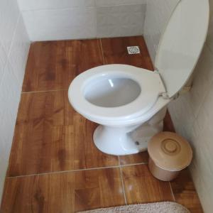 a white toilet in a bathroom with a wooden floor at Hostel São Francisco 3 in Votorantim
