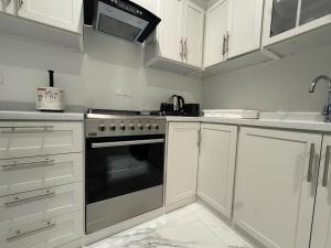 a kitchen with white cabinets and a stove top oven at Najd Cozy Apartments in Dammam +6 photos