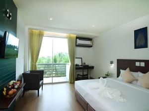 a bedroom with a large bed and a desk and a window at The Flora May Resort in Ban Nam Krachai +37 photos