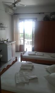 1 dormitorio con 2 camas y cocina con ventana en Anastasia en Áno Lekhónia