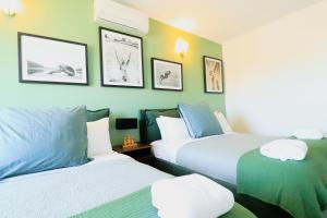 Pet Friendly Sleeps 8 Bowen Holiday House في بوين: سريرين في غرفة ذات جدران خضراء +111 صورة