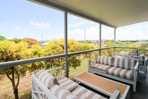 Pet Friendly Sleeps 8 Bowen Holiday House في بوين: بلكونه فيها كنب وطاولة وكراسي