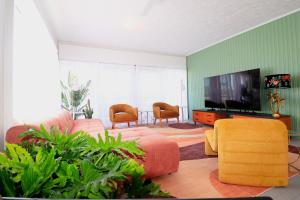 Pet Friendly Sleeps 8 Bowen Holiday House في بوين: غرفة معيشة مع أريكة وتلفزيون بشاشة مسطحة