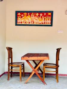 a wooden table and two chairs next to a painting at Ivy Cottage in Ahangama