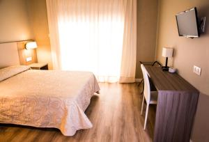 a bedroom with a bed and a desk with a television at Hotel Villa Ceuti in Ceuti