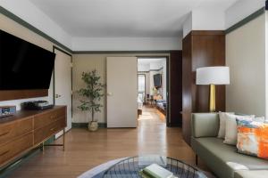a living room with a couch and a tv at The Printing House Hotel, Tapestry Collection By Hilton in Nashville