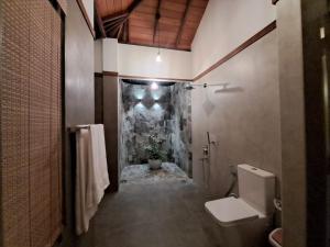 a bathroom with a toilet and a stone wall at River Shades Hotel in Hikkaduwa +56 photos