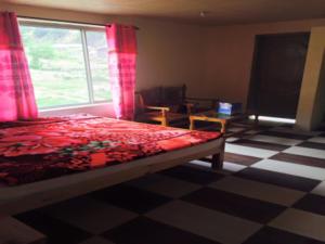 een slaapkamer met een bed en een raam en een geruite vloer bij Hotel Pine Track in Dargai