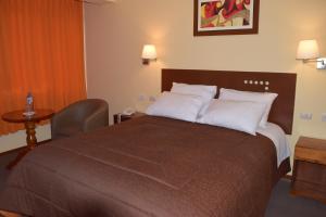 Habitación de hotel con cama grande con almohadas blancas en Illariy Hotel en Huancavelica