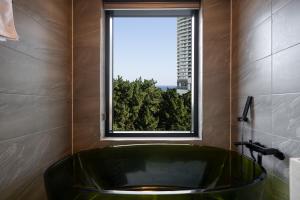 uma banheira verde numa casa de banho com uma janela em Hotel Hound Gangneung Gyeongpo em Gangneung mais 82 fotografias