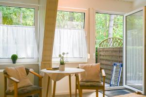 a room with a table and chairs and windows at Dünenhaus Fewos - Zum Strand 50m in Ueckeritz
