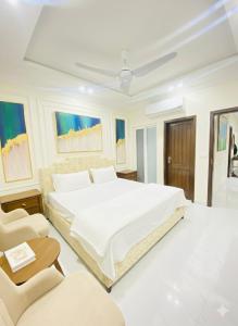 Appartments في فيصل آباد: غرفة نوم بيضاء مع سرير كبير وكراسي