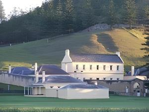 a large white house with a hill in the background at Fletcher Christian Holiday Hotel in Kingston