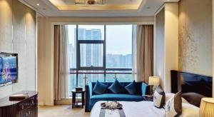 a hotel room with a blue couch and a large window at Hangzhou Huachen Fengting Hotel in Hangzhou