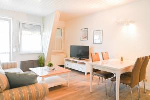 a living room with a table and a tv at Dünenhaus Fewos - Zum Strand 50m in Ueckeritz