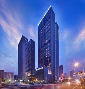 New Century Grand Hotel Hangzhou Shengtai في هانغتشو: مبنى طويل وكبير في مدينة في الليل
