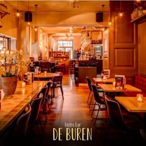 a restaurant with tables and chairs and a kitchen at Slapen bij De Buren in Alkmaar +5 photos