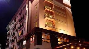 a tall building with many windows at night at Bonito Chinos Hotel in Nakhon Sawan