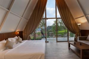 a bedroom with a bed and a large window at Triangle Valley in Ooty