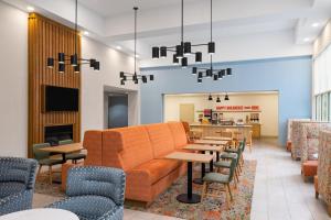 Hampton Inn & Suites Southern Pines-Pinehurst في Aberdeen: غرفة انتظار مع أريكة وطاولات وكراسي