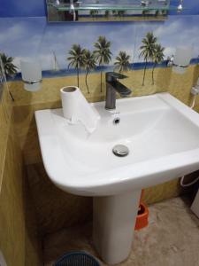 uma pia branca em um banheiro com palmeiras na parede em Forest Paddy Homestay em Ella mais 46 fotografias