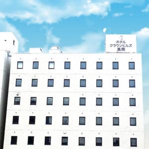 a white building with a sign on top of it at Hotel Crown Hills Takaoka in Takaoka