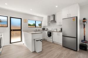 a kitchen with white cabinets and a stainless steel refrigerator at Within Range in Papamoa