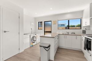 a white kitchen with a sink and a counter at Within Range in Papamoa