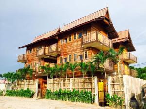 Un edificio de madera con palmeras delante. en Kampong Pinang Sebatang Melaka, en Pengkalan Balak