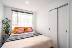 ein Schlafzimmer mit einem Bett mit rosa und orangefarbenen Kissen in der Unterkunft Opulent Haven, Designer Luxury, Expansive Space in Lower Hutt